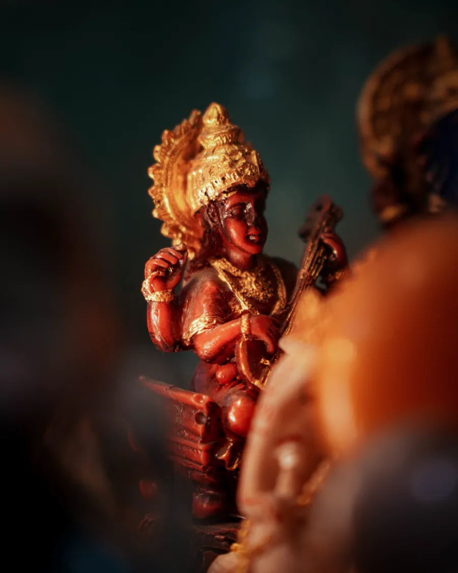 Ganesh idol in sindoor red and gold, lit by warm light